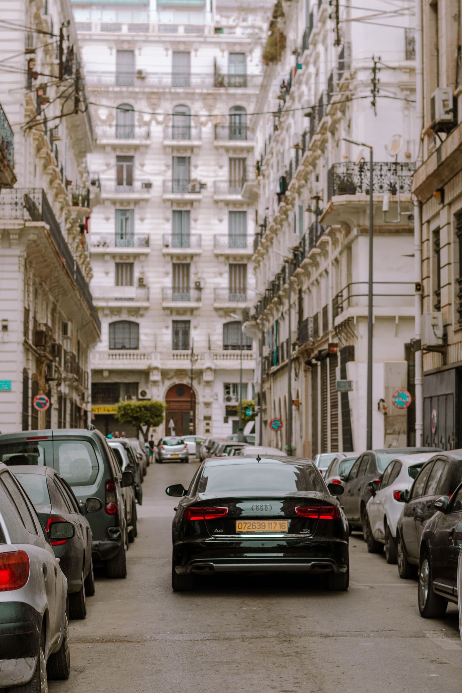 Une Audi noire garée parmi des rangées de voitures dans une rue étroite d’Alger Centre